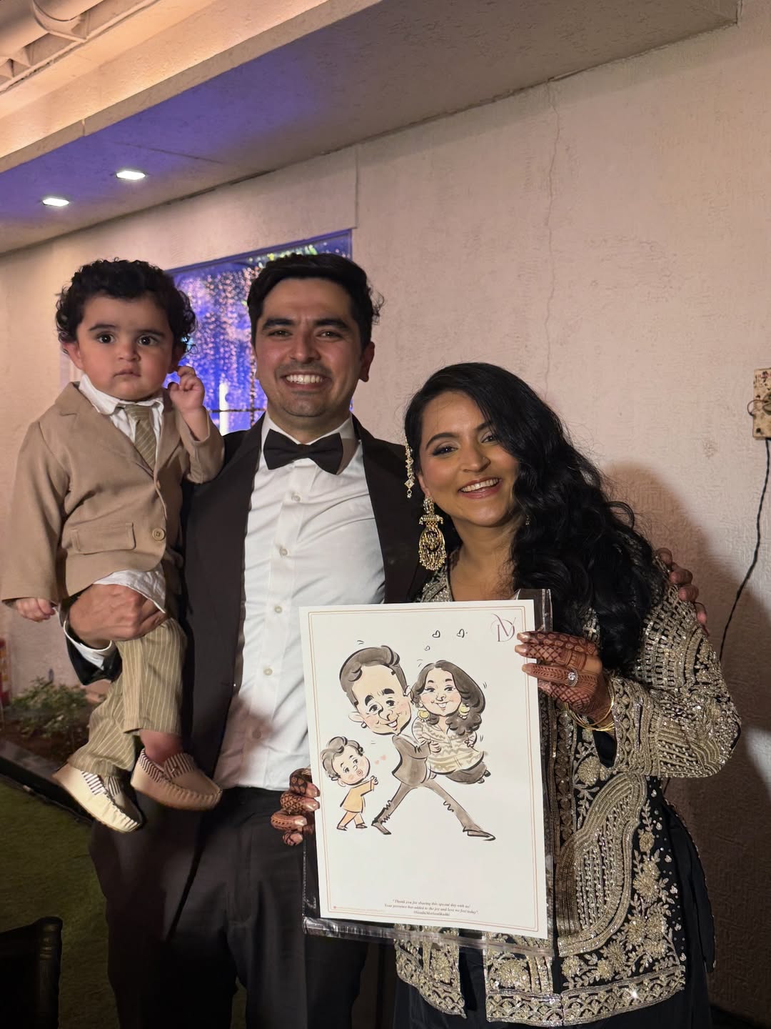 Young couple with toddler holding a live family caricature at an evening reception