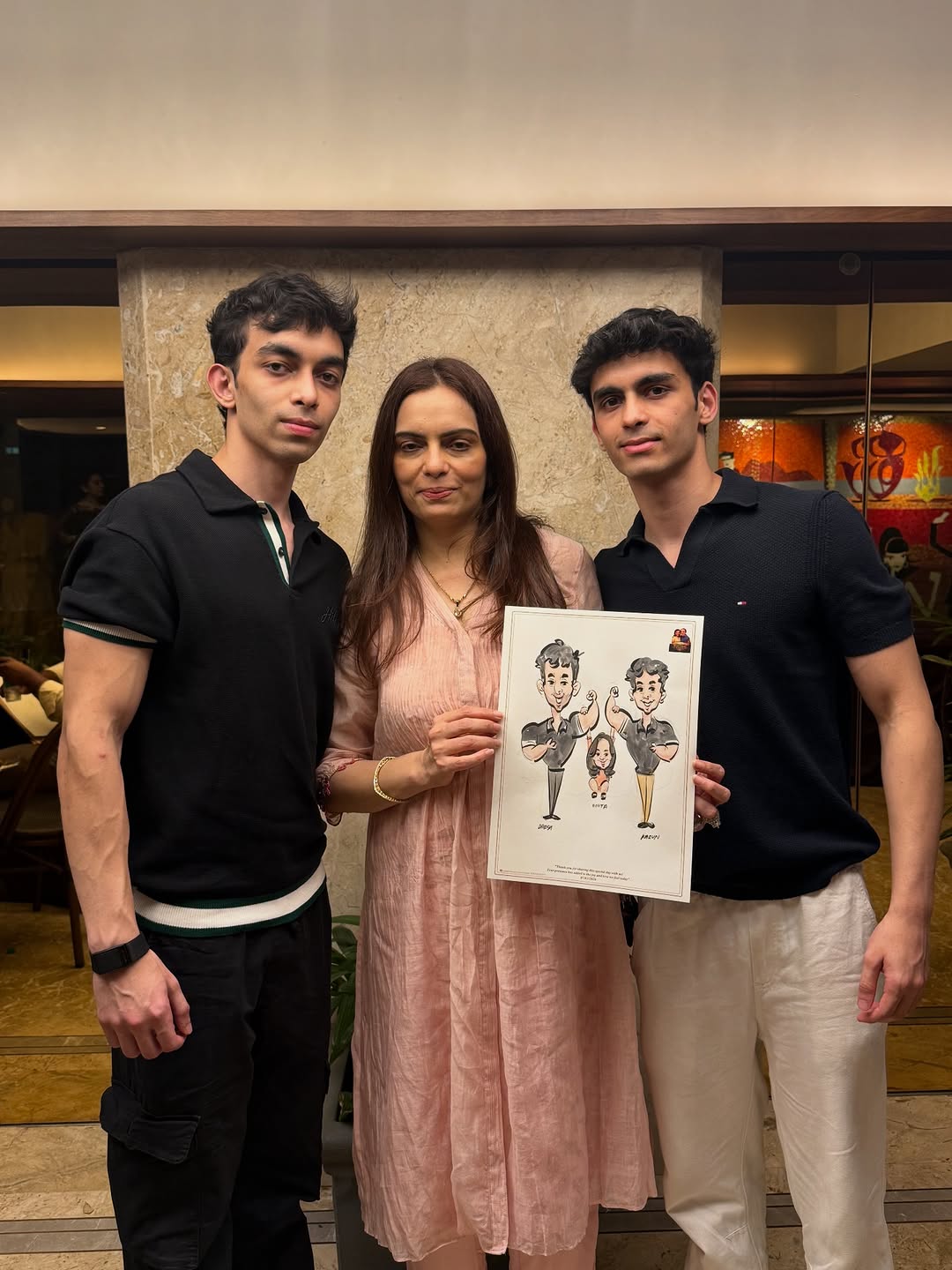 Mother with her two grown sons holding a live family caricature at a celebration