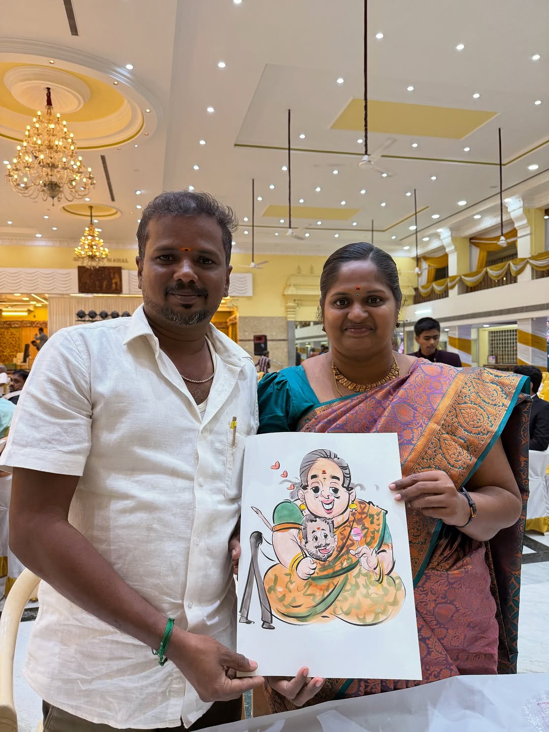South Indian couple holding a live watercolor caricature at their wedding